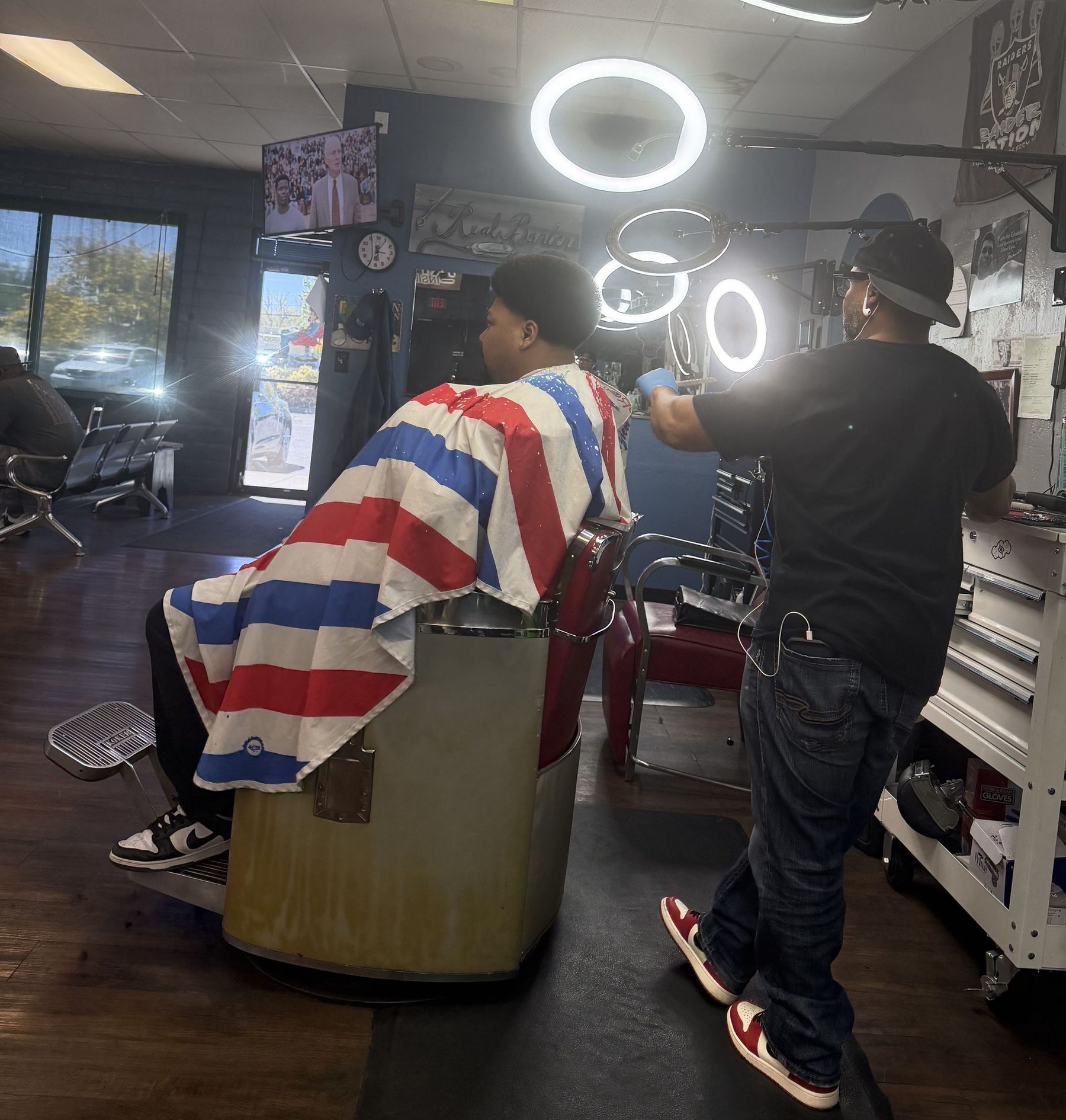 A client in the vintage chair under ring lights at Top Notch Barber Shop, mid-fade